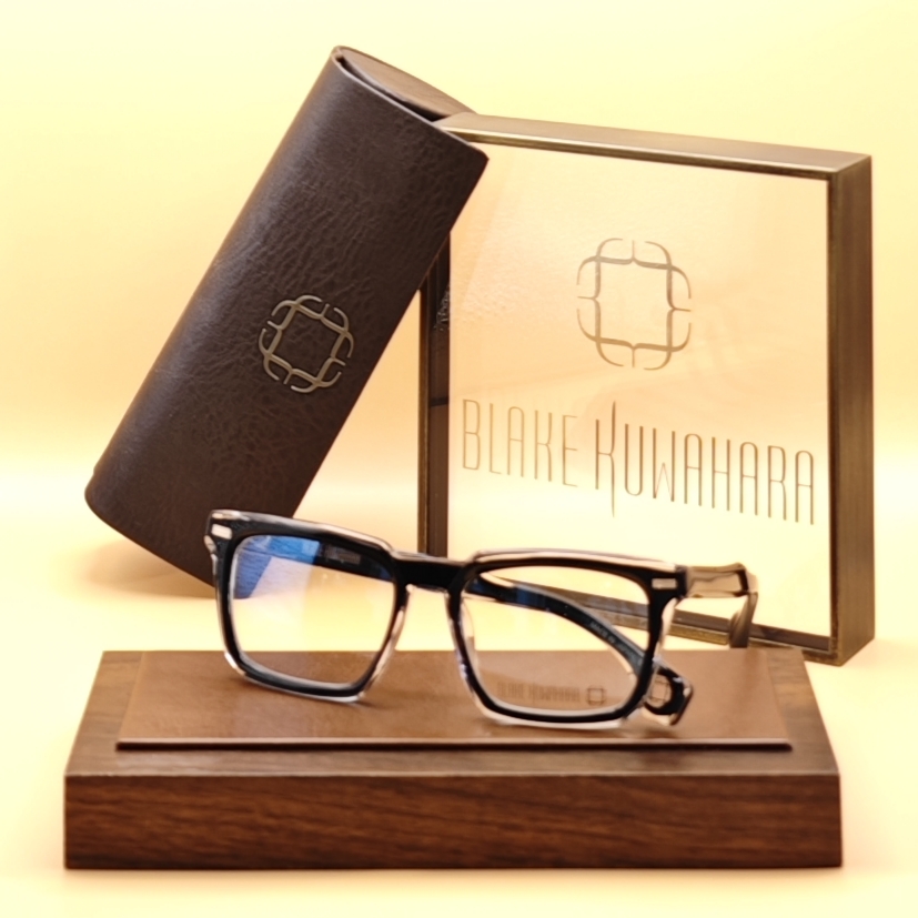 Blake Kuwahara's Proctor rectangular optical frames in black layered over clear acetate, with a distinctive split color design.