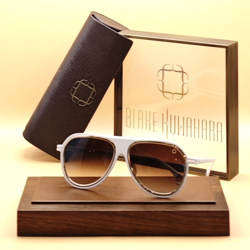 Blake Kuwahara's Easton aviator-style sunglasses with thick white rims, gold metal accents, and brown gradient lenses.