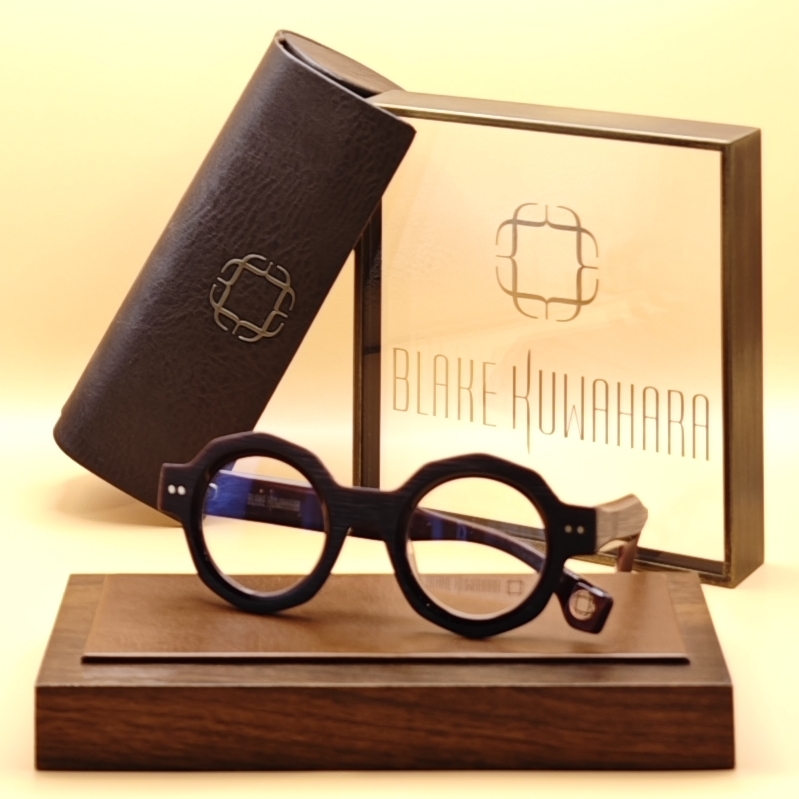 Blake Kuwahara's BK 1029 distinctly round optical frames with a textured, matte dark wood-effect finish and visible rivets.