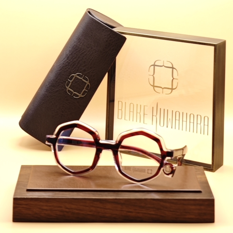 Blake Kuwahara's Loos bold geometric glasses with a translucent red/maroon outer rim layered over a clear hexagonal frame.