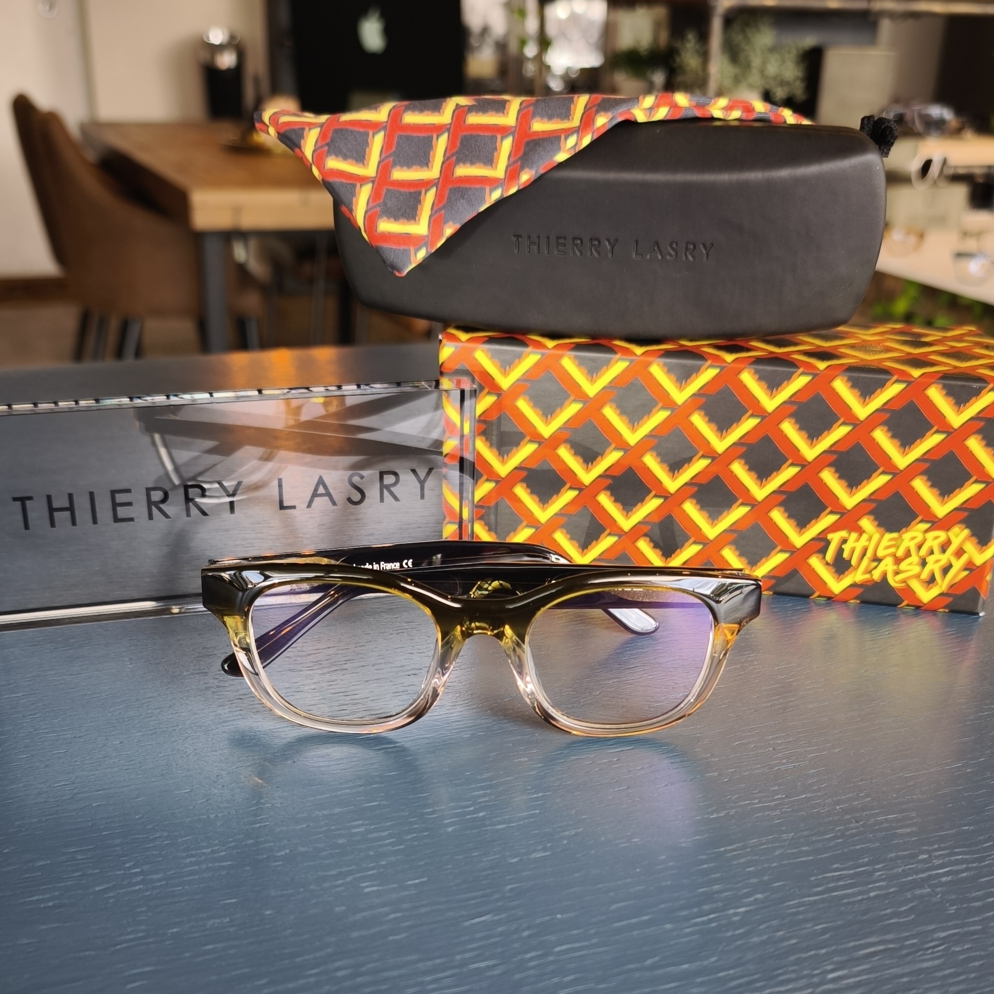 Thierry Lasry optical glasses featuring a soft rectangular silhouette with a vertical gradient. The frames transition from a dark, translucent forest green at the brow to a clear, pale peach-pink at the base. Displayed at The Focal Rooms.