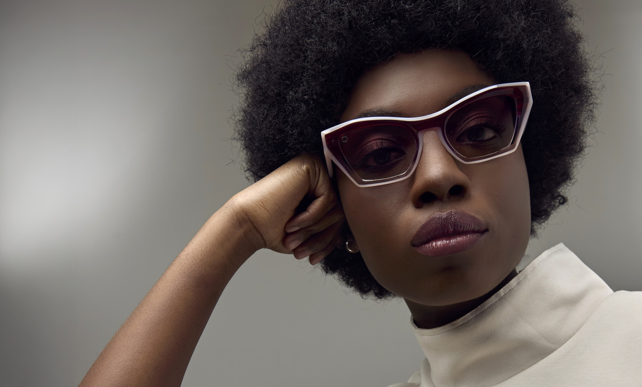 High-angle close-up of a female model with straight bangs wearing Blake Kuwahara deep red, chunky cat-eye eyeglasses.